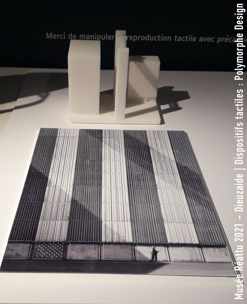 Au premier plan se trouve l'interpr&eacute;tation tactile de l'Autoportait. Derri&egrave;re se trouve la maquette 3D des b&acirc;timents industriels, l'ombre des b&acirc;timents hors-champs se projetant sur la fa&ccedil;ade principale, formant de larges diagonales.